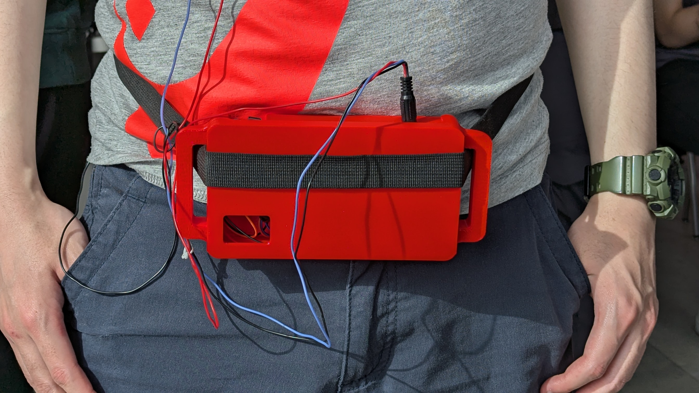 Red 3D-printed enclosure worn on torso with electrode leads routed to chest positions