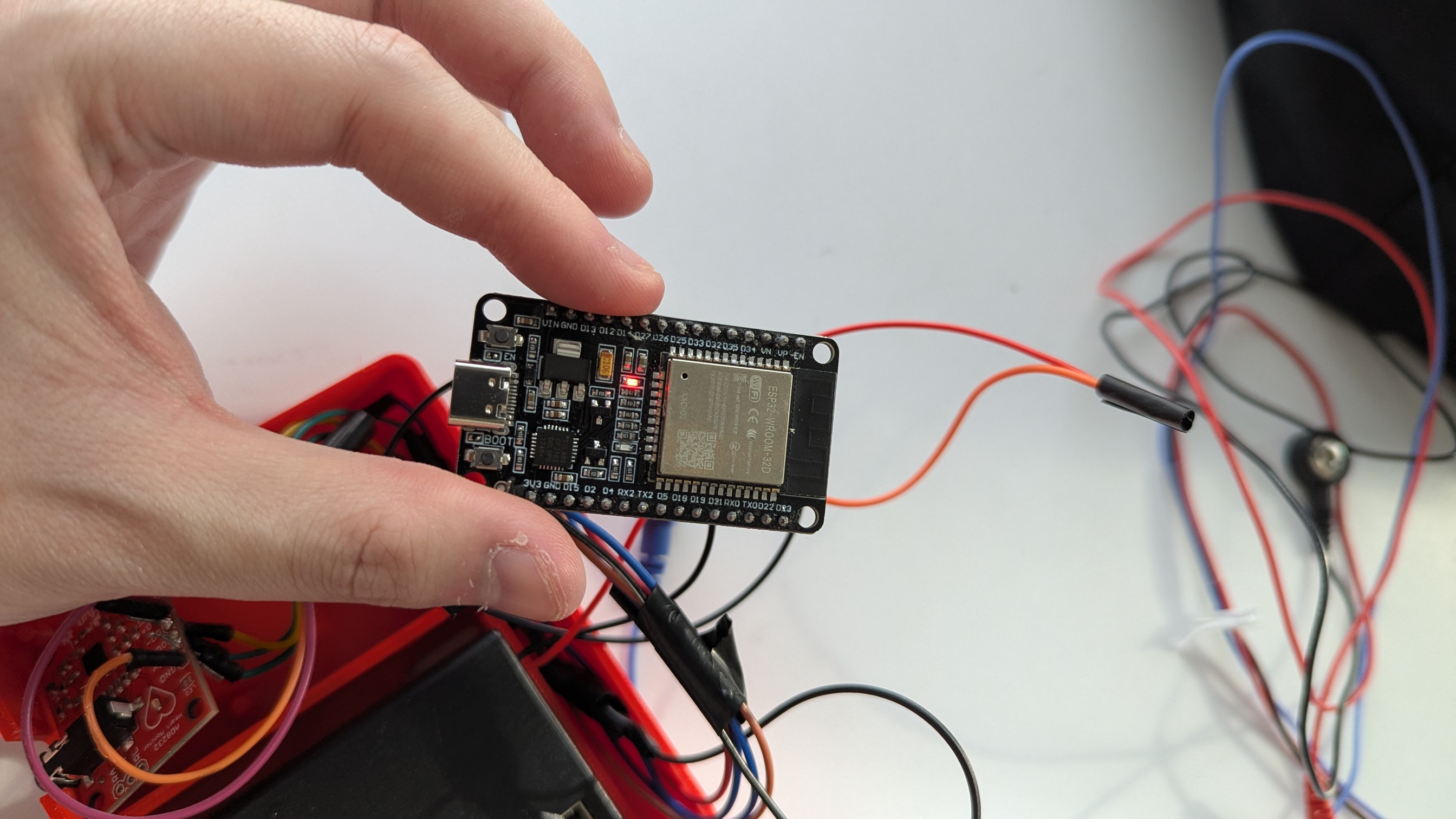 ESP32 development board held above components with wiring visible